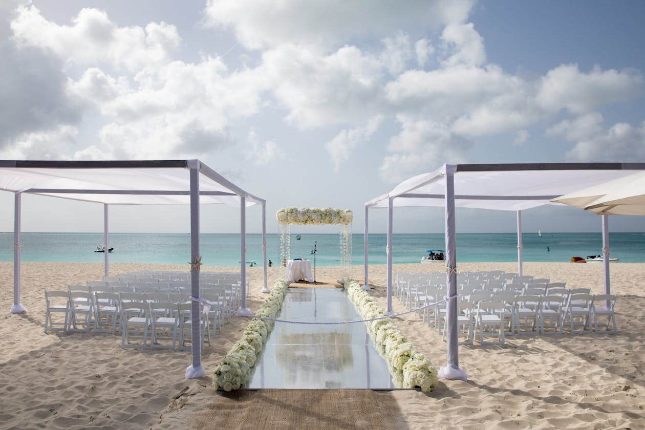 All-white tropical wedding with white canopies over seating at beach in Turks and Caicos | PartySlate