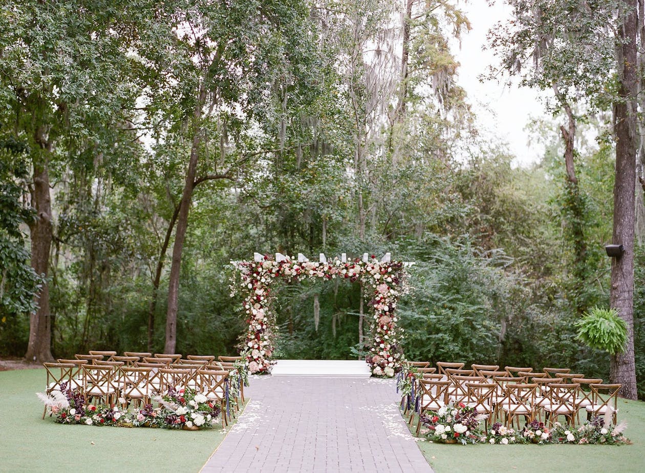 Garden wedding with pink and red floral wedding arch | PartySlate