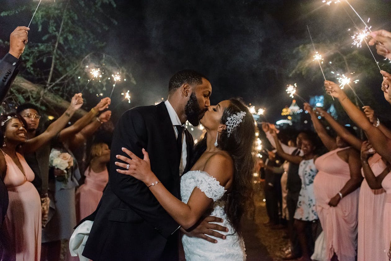 Couple kisses during a sparkler send off | PartySlate