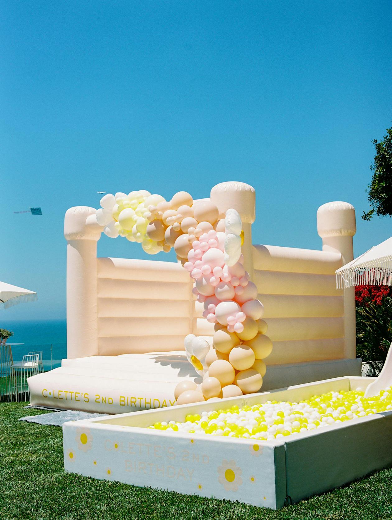 yellow bounce house covered in pink and yellow balloons | PartySlate
