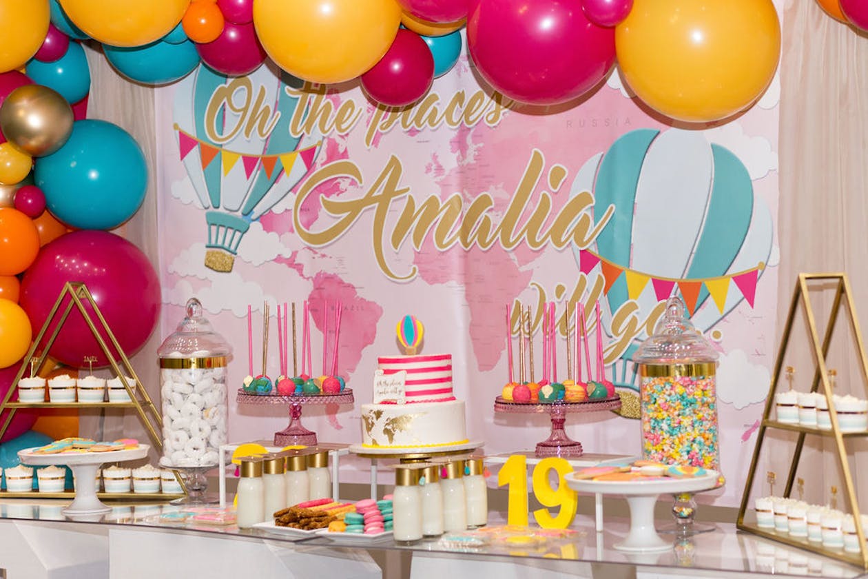 colorful graduation party food table with balloons and personalized food | PartySlate