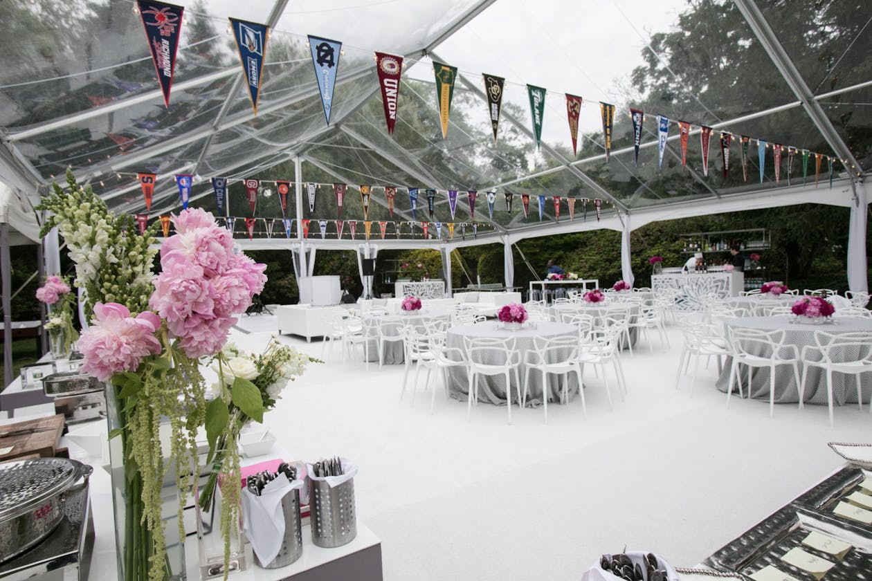 school flags hanging from tented graduation party | PartySlate