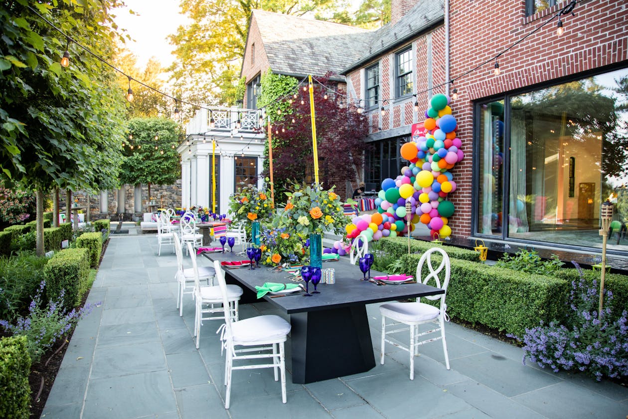 colorful balloon installment in backyard for a graduation party with table and chairs set for dinner | PartySlate