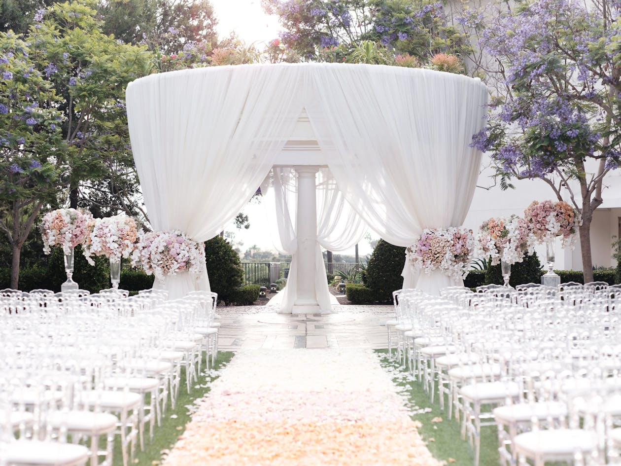 Outdoor garden wedding with arbor covered in white drapery | PartySlate