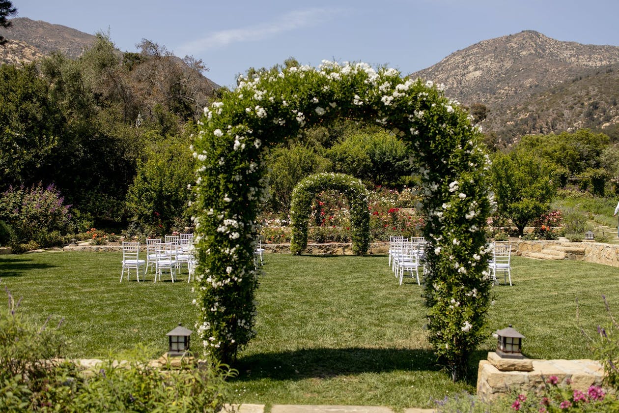 Wedding ceremony with double greenery arches | PartySlate