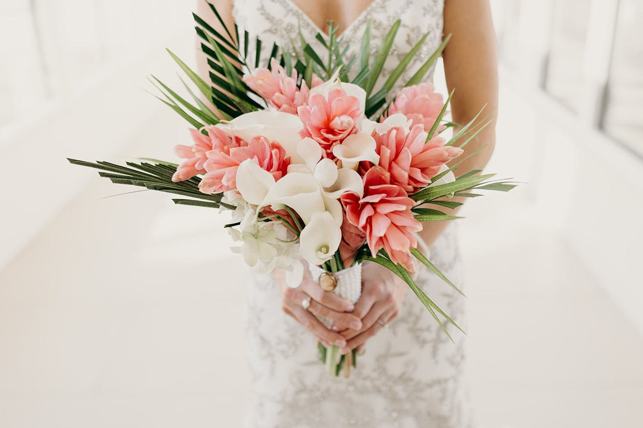 Tropical wedding bouquet with pink ginger, white calla lilies, and green fronds | PartySlate