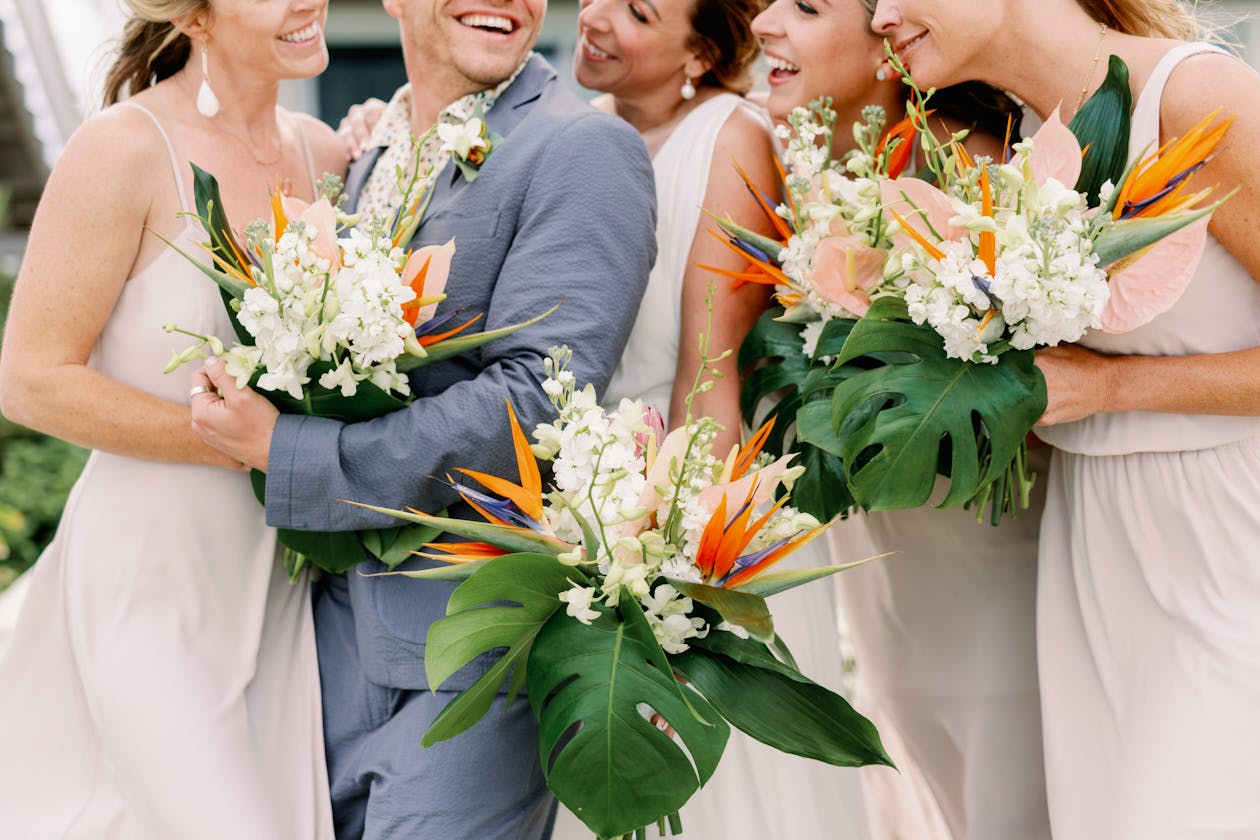 Wedding party hold tropical bouquets with giant green leaves, birds of paradise, and white blooms | PartySlate