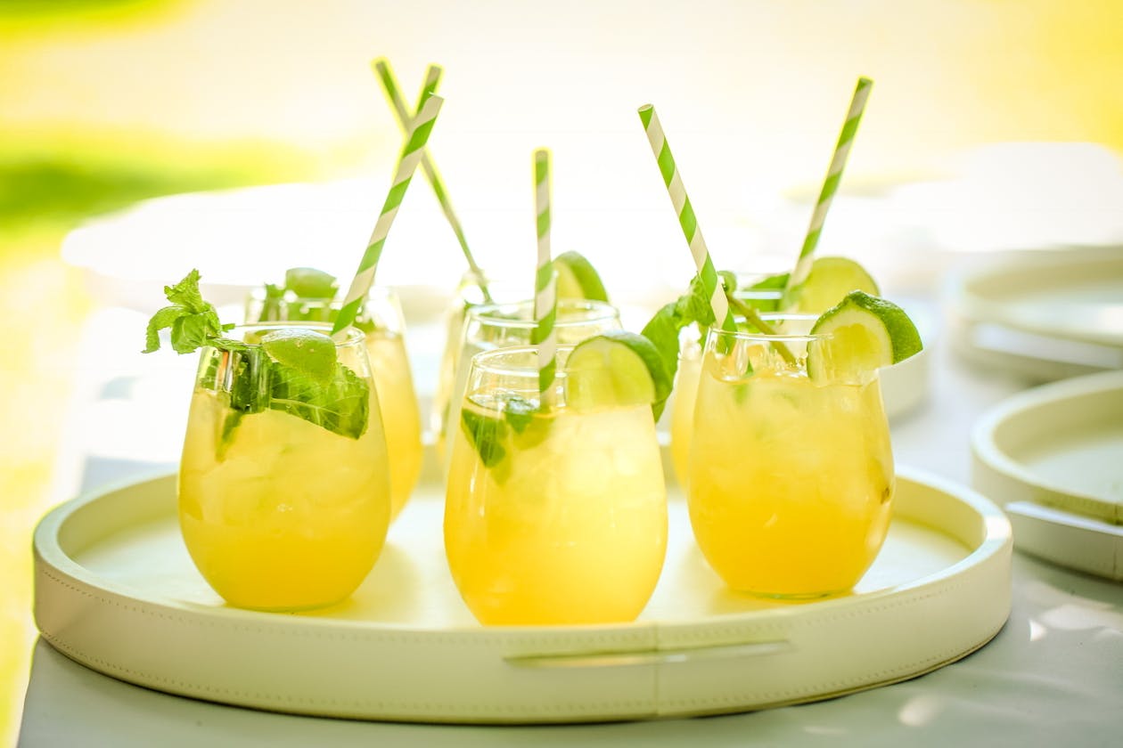 Yellow tropical cocktails with green and white stripped straws and limes | PartySlate