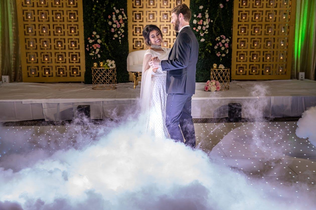 Couple dances through fog with lights in backdrop | PartySlate