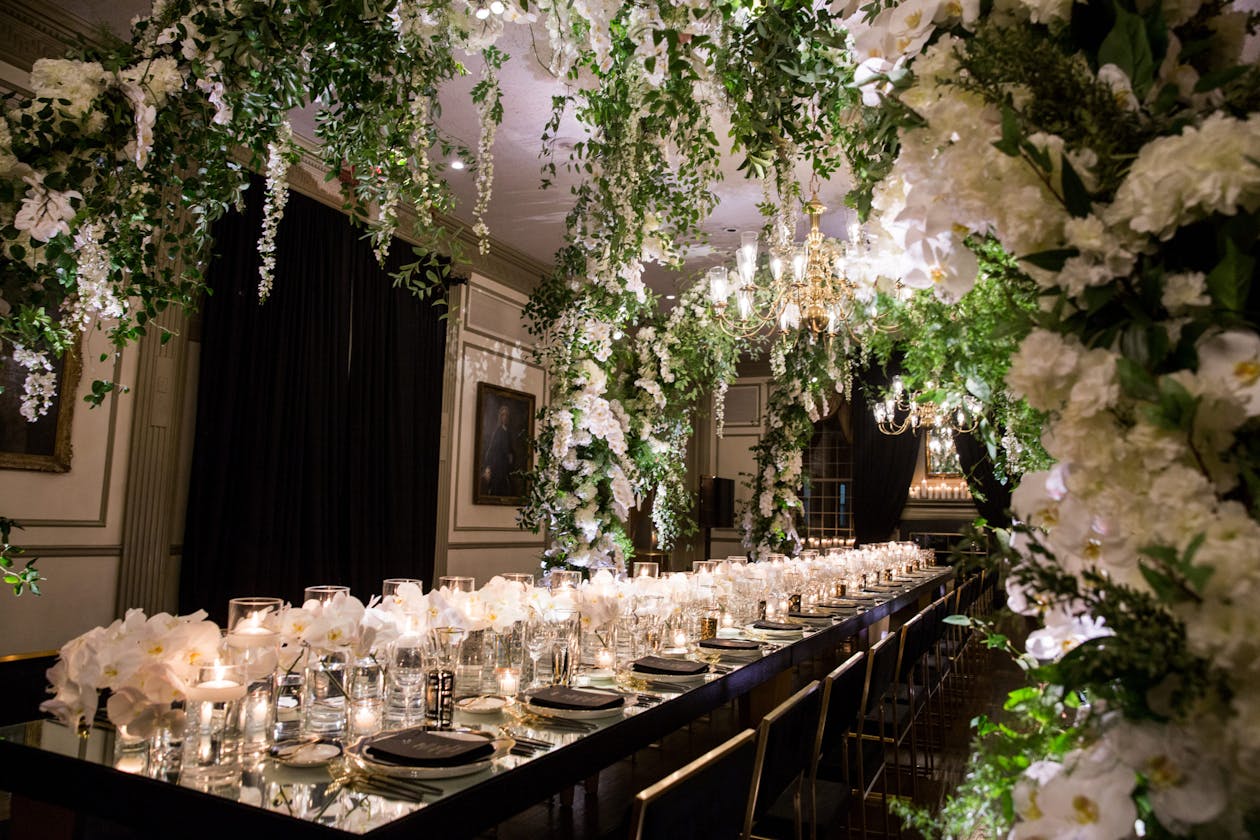 Wedding king's table with overarching green and white florals | PartySlate
