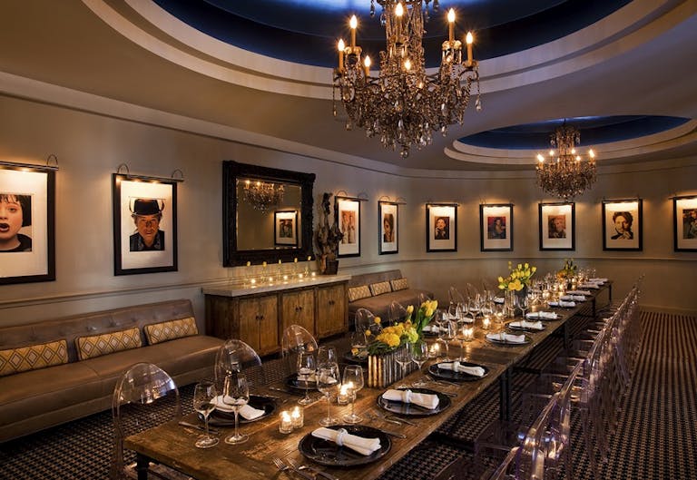 Private dining at hotel zaza in dallas with gold accents, chandelier, famed portraits on walls, and table set | PartySlate