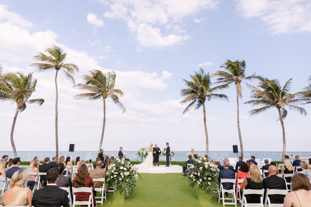 Wedding ceremony surrounded by palm trees at The Breakers Palm Beach | PartySlate
