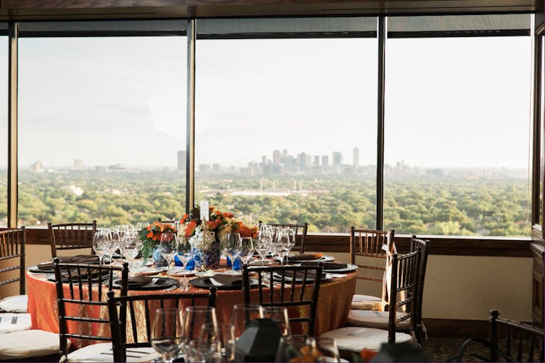 Private dining restaurants in Dallas main dinning room with chairs and tables set with skyline in the background | PartySlate