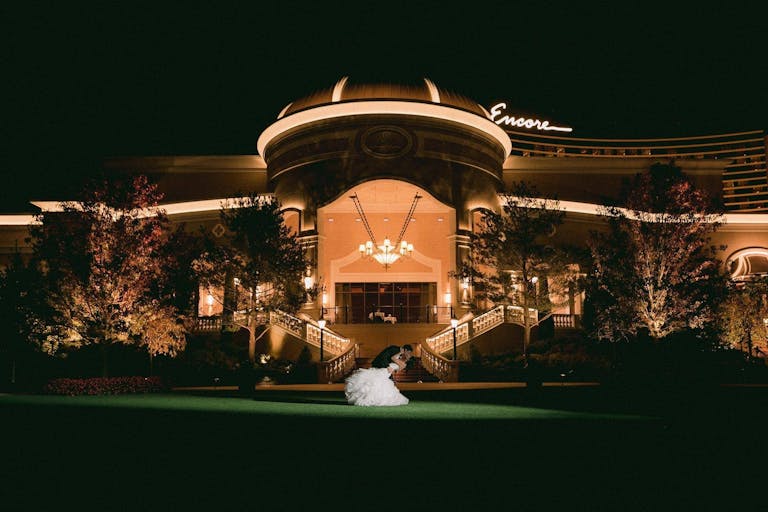 Couple in front of grand luxury wedding venue at night | PartySlate