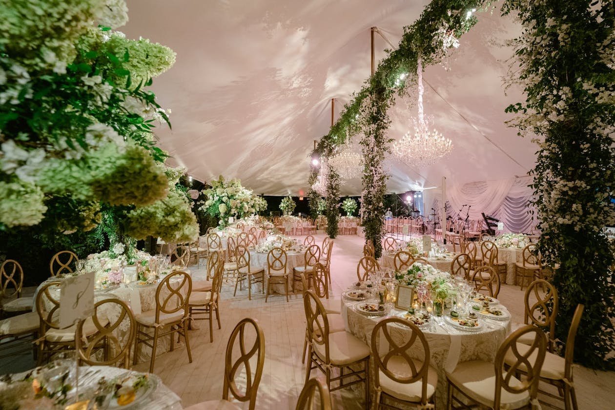 Lavish pole tent wedding with greenery and chandeliers | PartySlate