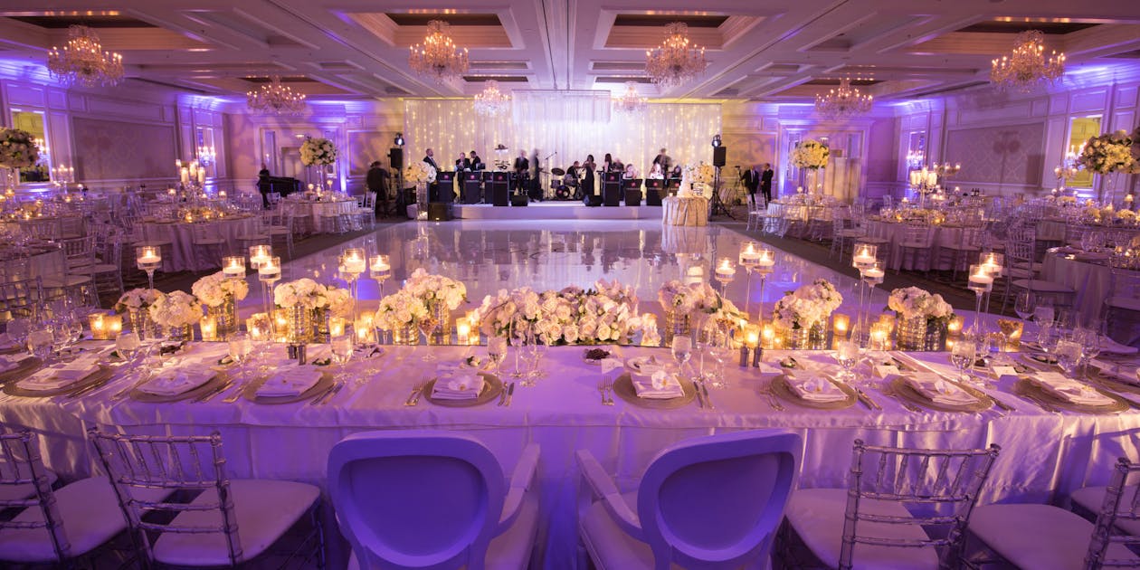 Classic wedding head table looking onto the dance floor with a mood lighting with a purple hue | PartySlate