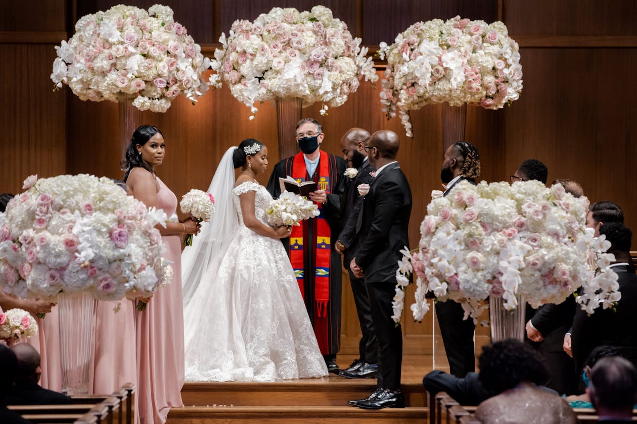 Couple exchanges vows surrounded by pink and white flowers | PartySlate