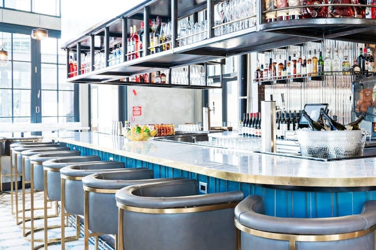 Officina bar area with grey high top chairs and bottles hanging above bar | PartySlate