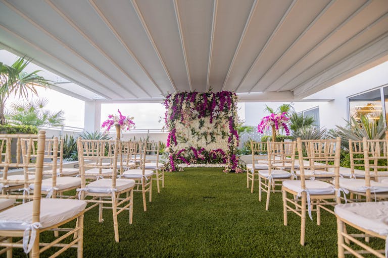 tropical outdoor wedding in miami with floral wall at the end of wedding aisle | PartySlate