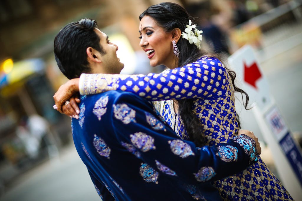 South Asian couple in blue traditional attire embrace | PartySlate