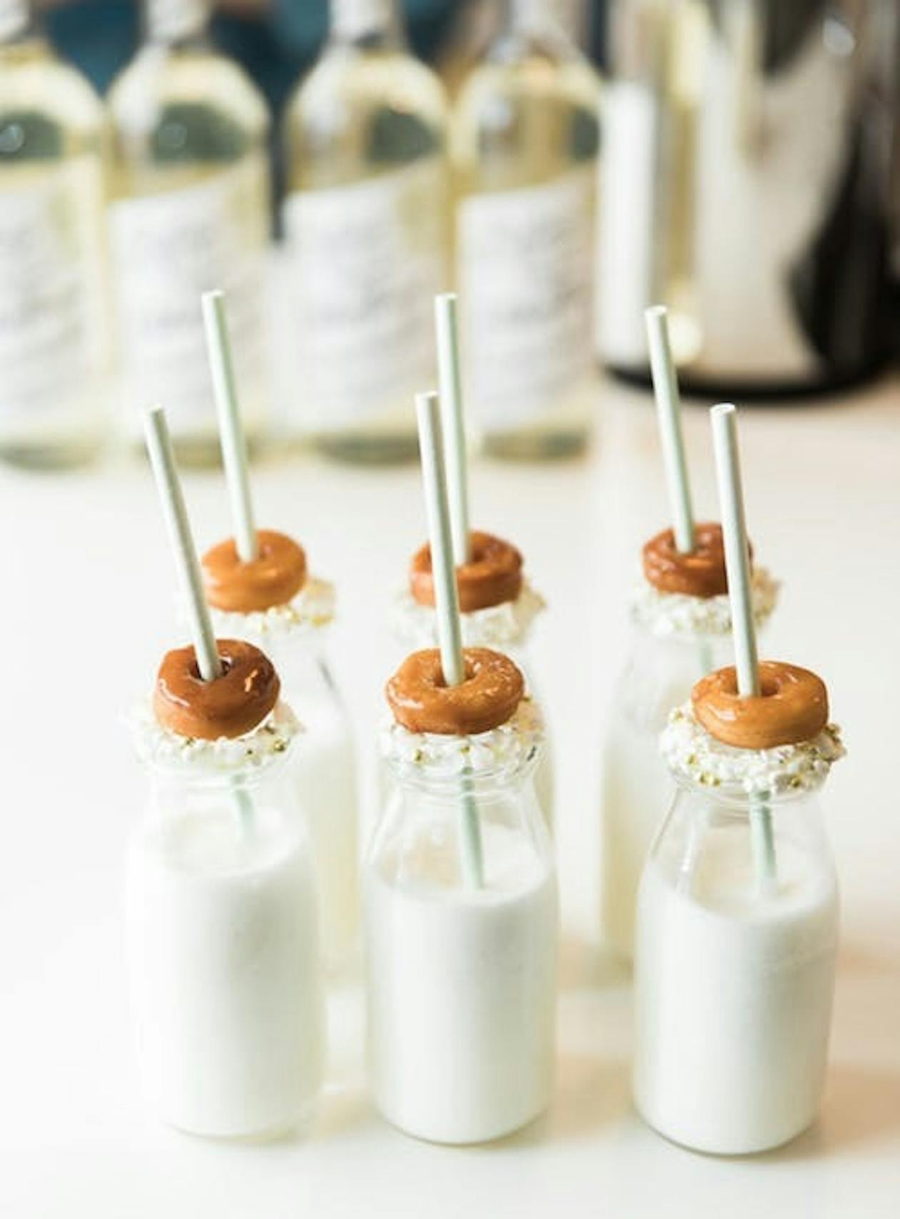 milk in glass milk cartons with a straw and a donut sitting on top of each one | PartySlate