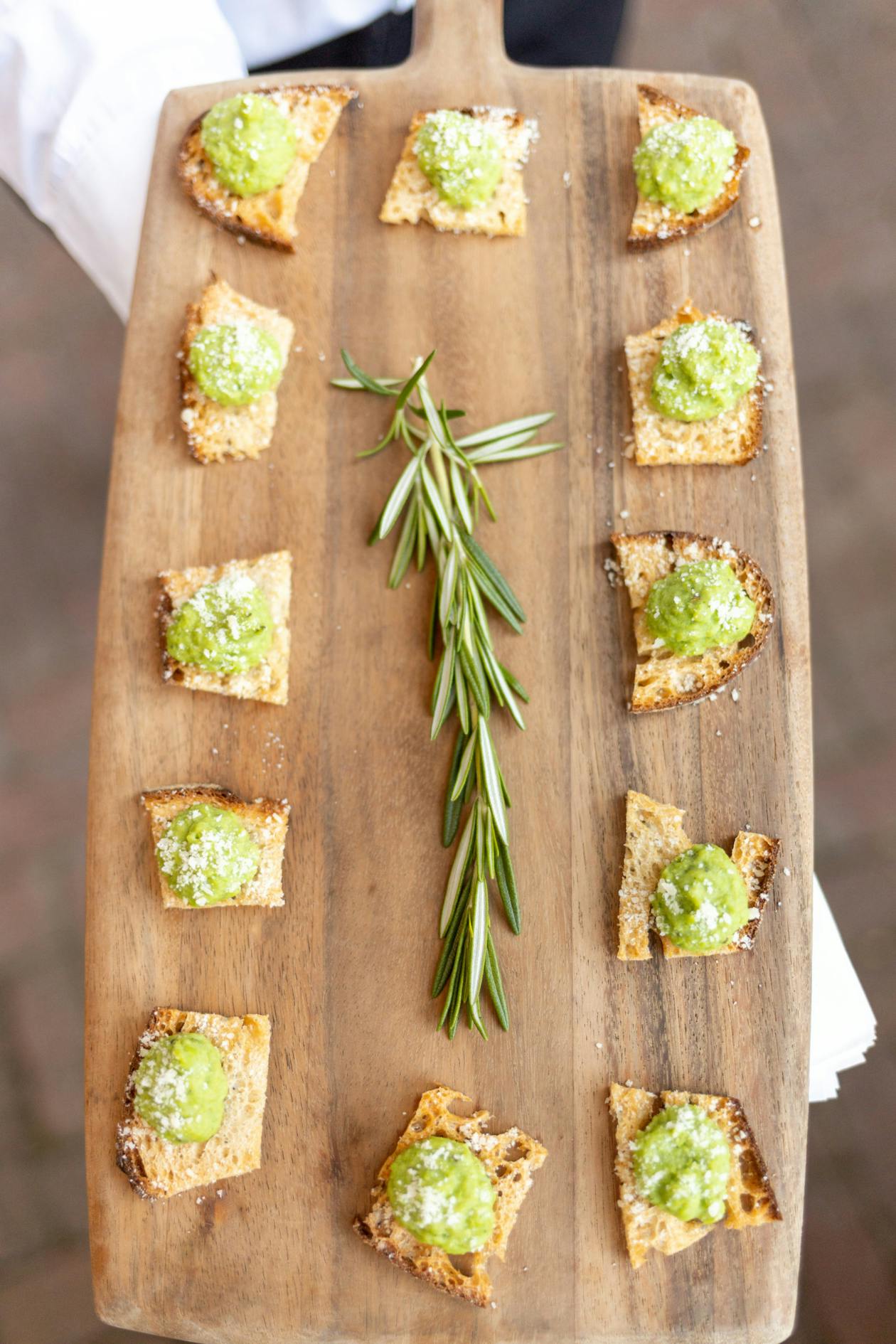 small pieces of avocado toast on a wood platter for serving at a baby shower | PartySlate