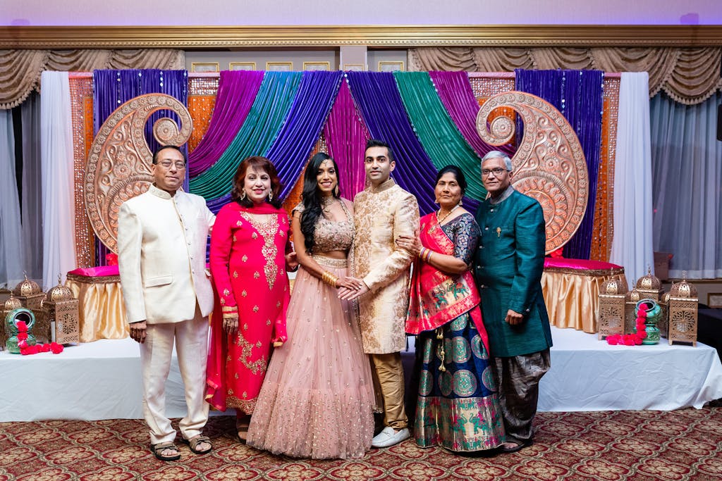 Bride and groom pose with parents at Sangeet celebration | PartySlate