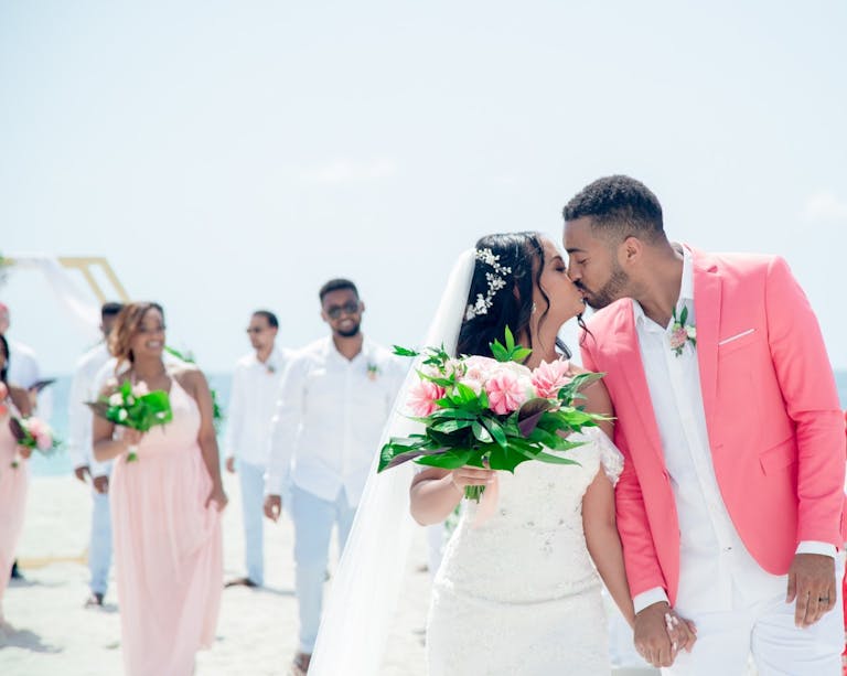 wedding on the beach in miami with couple walking down aisle and wedding party following behind them | PartySlate