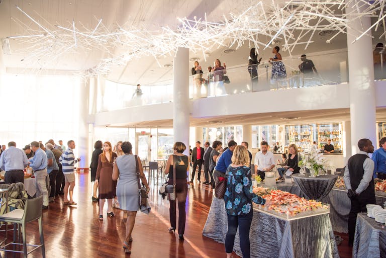 opening party at sequoia in dc with people standing around and eating from buffets with a crystal chandelier hanging above | PartySlate