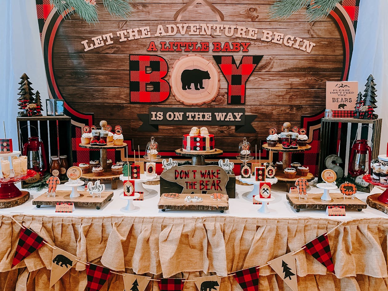 lumberjack themed baby shower with wood accents and red checkered print cake and themed food on a table | PartySlate