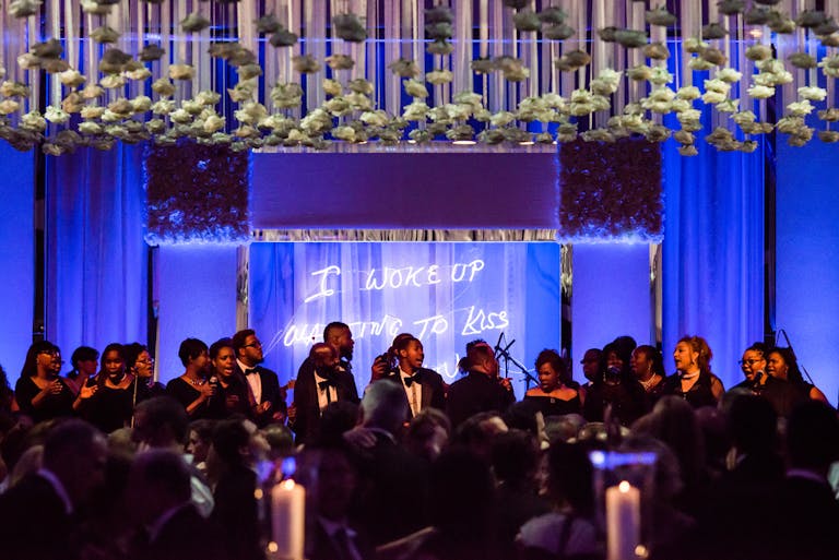 The Gold Coast All Stars perform at wedding with blue uplighting and suspended floral ceiling décor | PartySlate