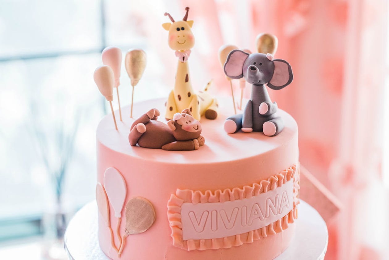 pink baby shower cake with monkey elephant and giraffe on top | PartySlate