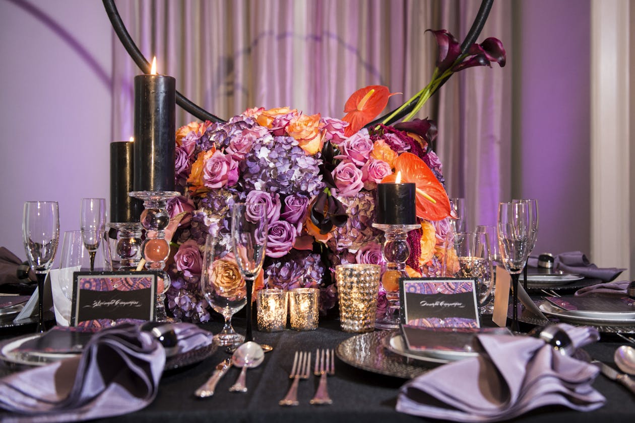 Edgy wedding centerpiece with purple and orange flowers and black candles | PartySlate