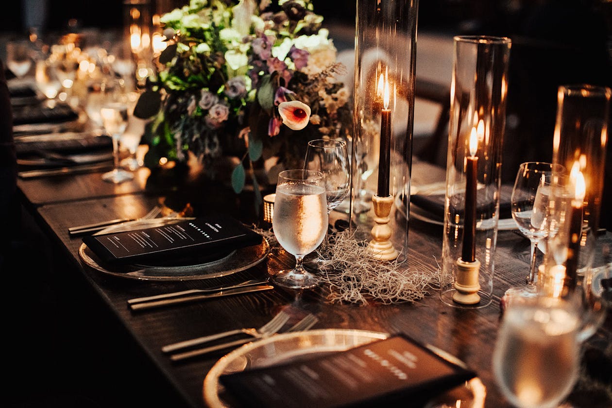 Dark and moody wedding tablescape with flowers and black tapered candles | PartySlate