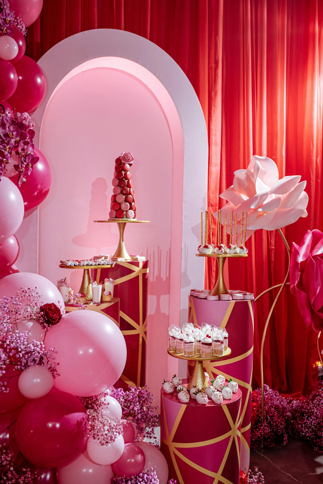 pink macaroon tower with dessert display at baby shower surrounded by pink balloons and décor | PartySlate
