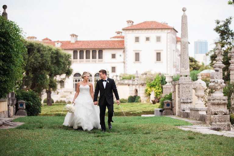 couple walking outside their miami wedding venue estate grounds with estate in the background | PartySlate