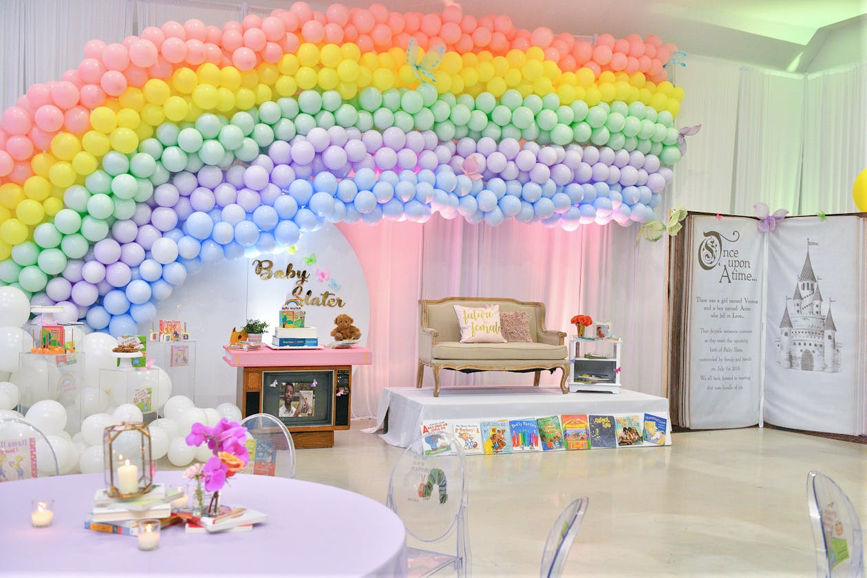 Book themed baby shower with rainbow balloon arch | PartySlate