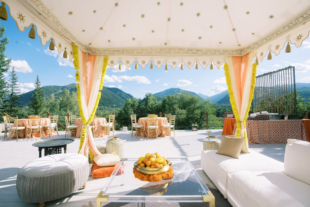 Indian wedding sangeet with gold and blush tenting set against mountainous backdrop | PartySlate
