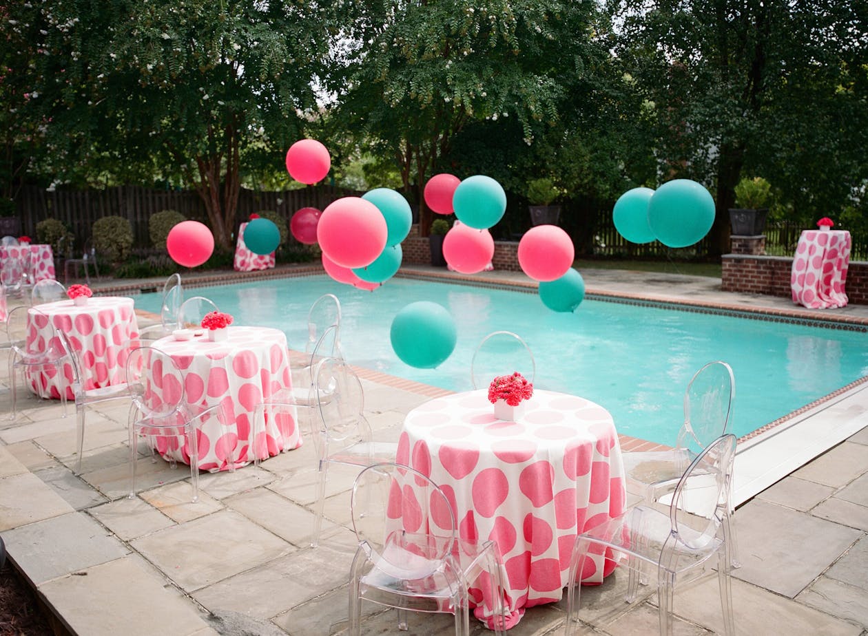 Poolside baby shower with pink table linen and pink and blue balloons | PartySlate
