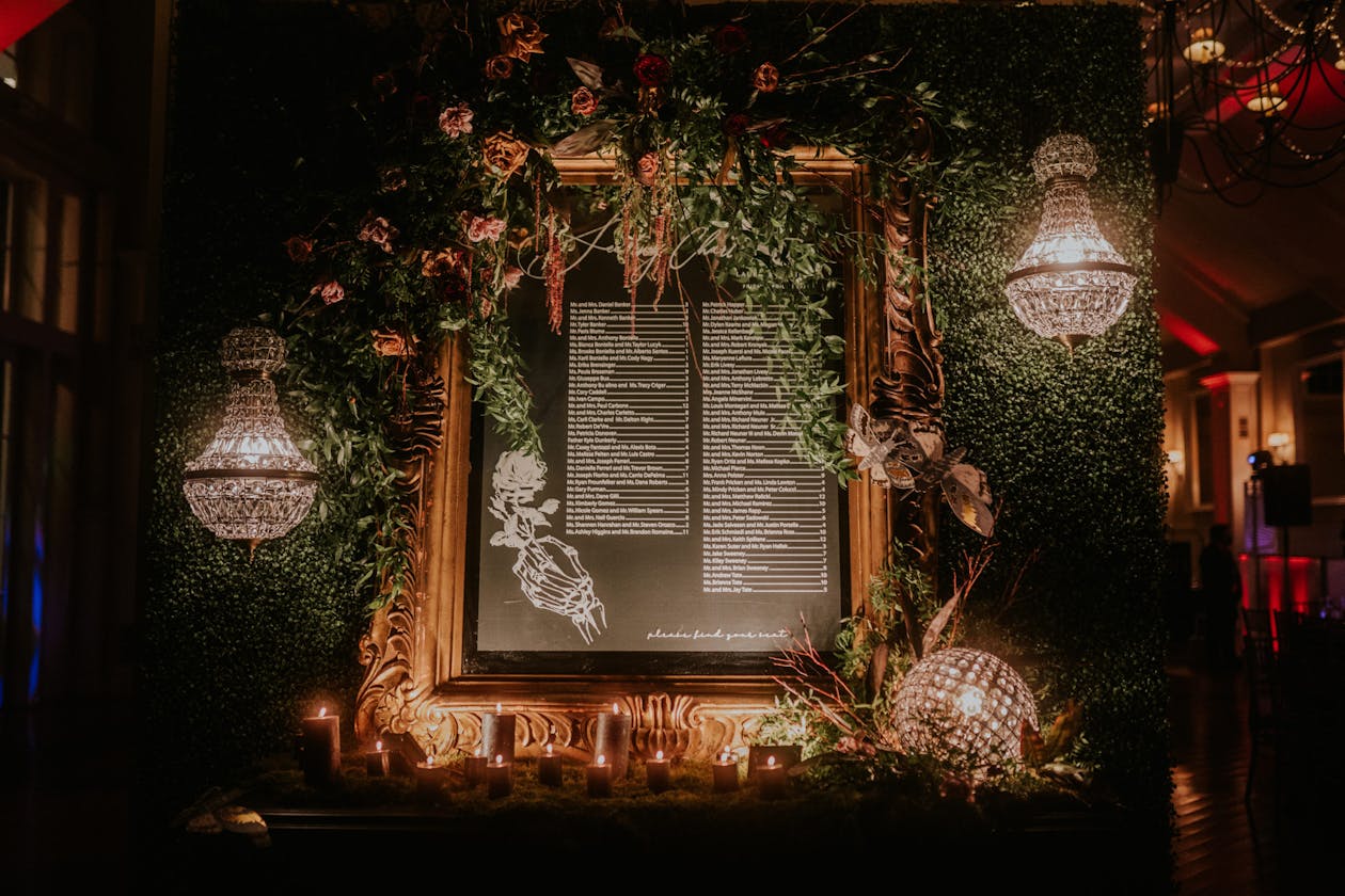 Black chalk wedding seating chart in gold frame surrounded by greenery | PartySlate