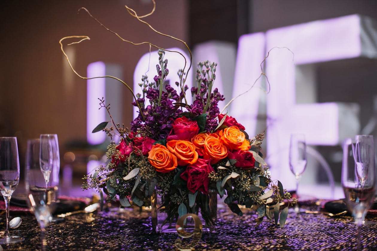 Moody wedding centerpiece with orange and purple flowers | PartySlate