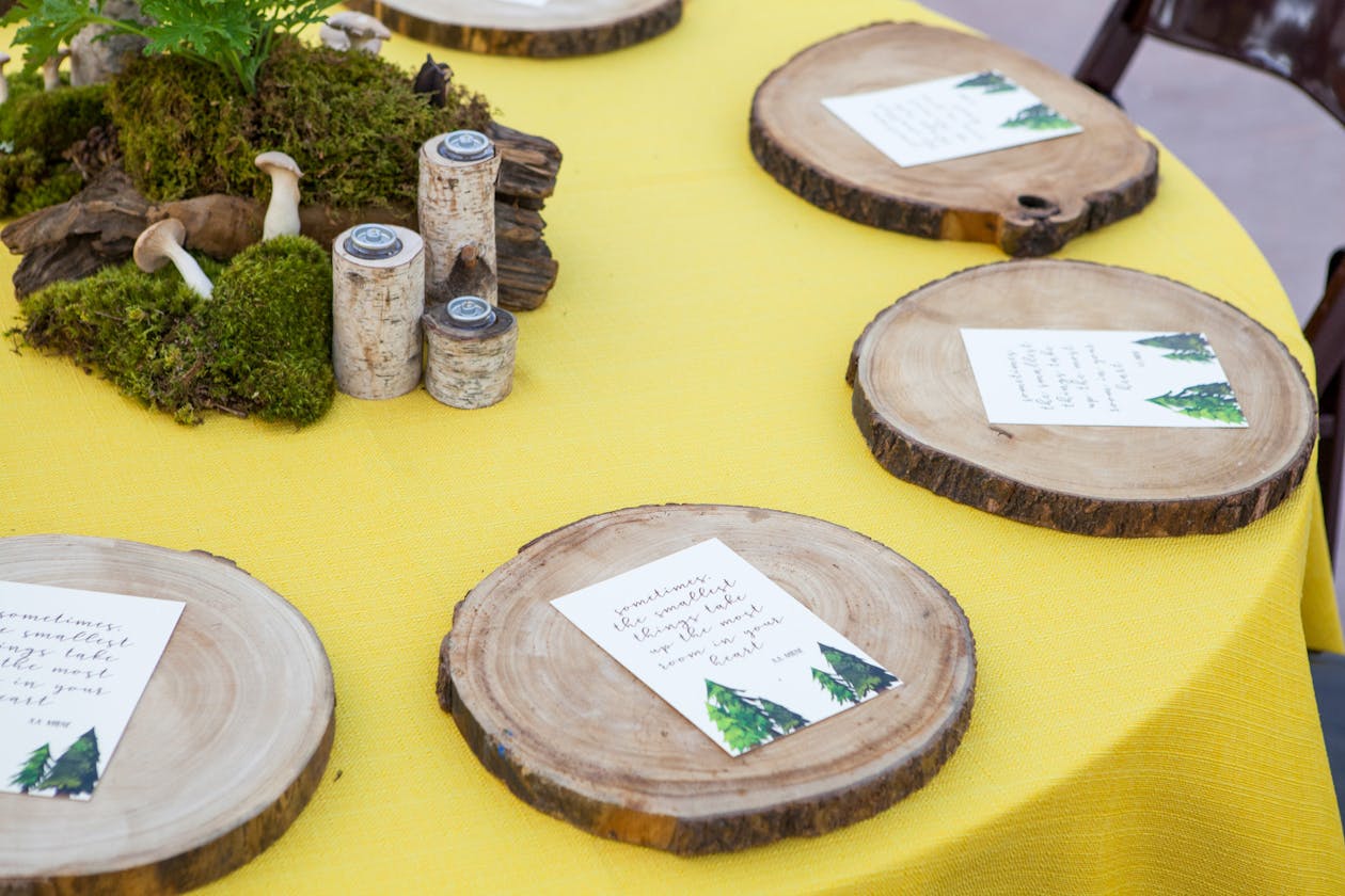 Woodsy yellow reception table with tree trunks, mushrooms, and moss | PartySlate