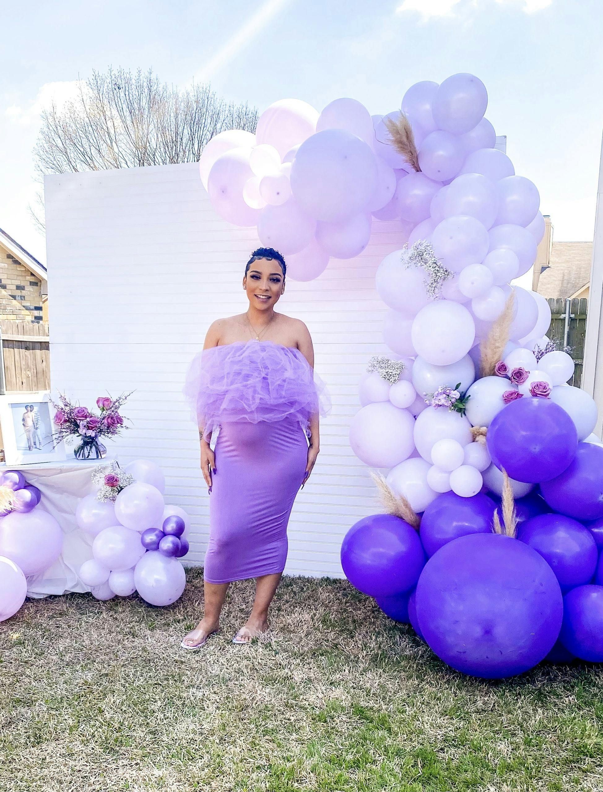 expectant mother standing in front of purple balloon installation outside at baby shower in Dallas Texas | PartySlate