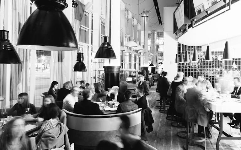 black and white photo of St. Cecilia restaurant in atlanta gorgia with guests seated and eating | PartySlate