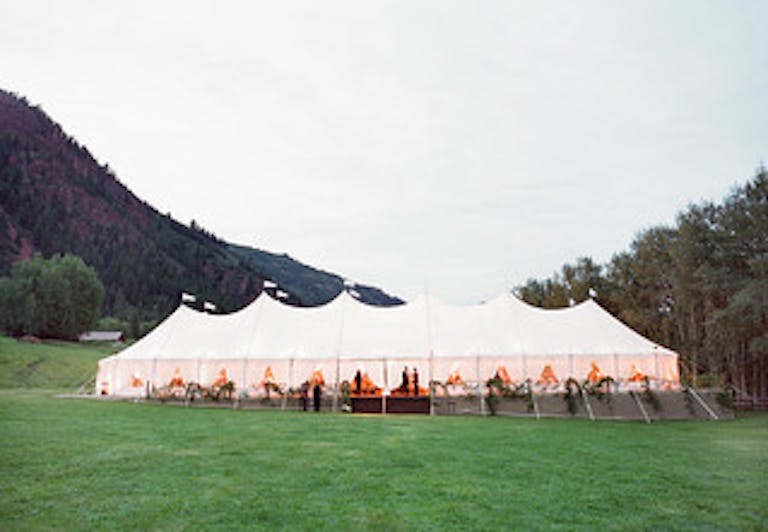outdoor tented wedding with rocky mountains in the background | PartySlate