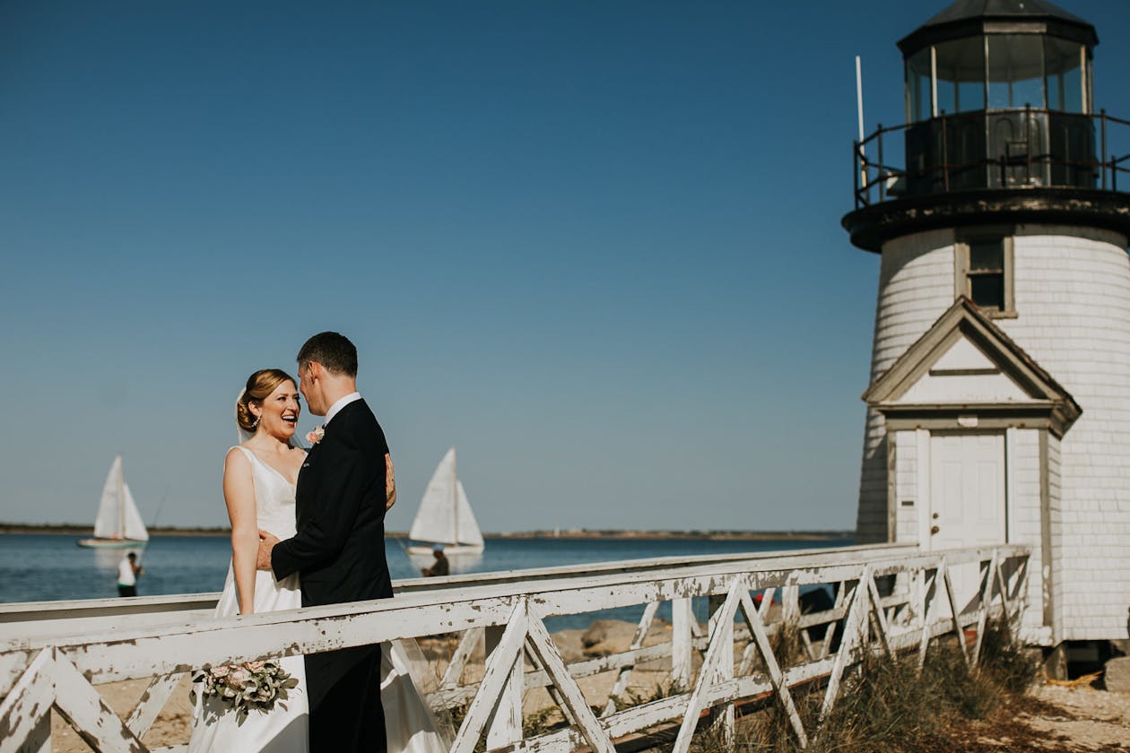 couple getting married at the nantucket hotel standing on the pier by the lighthouse | PartySlate