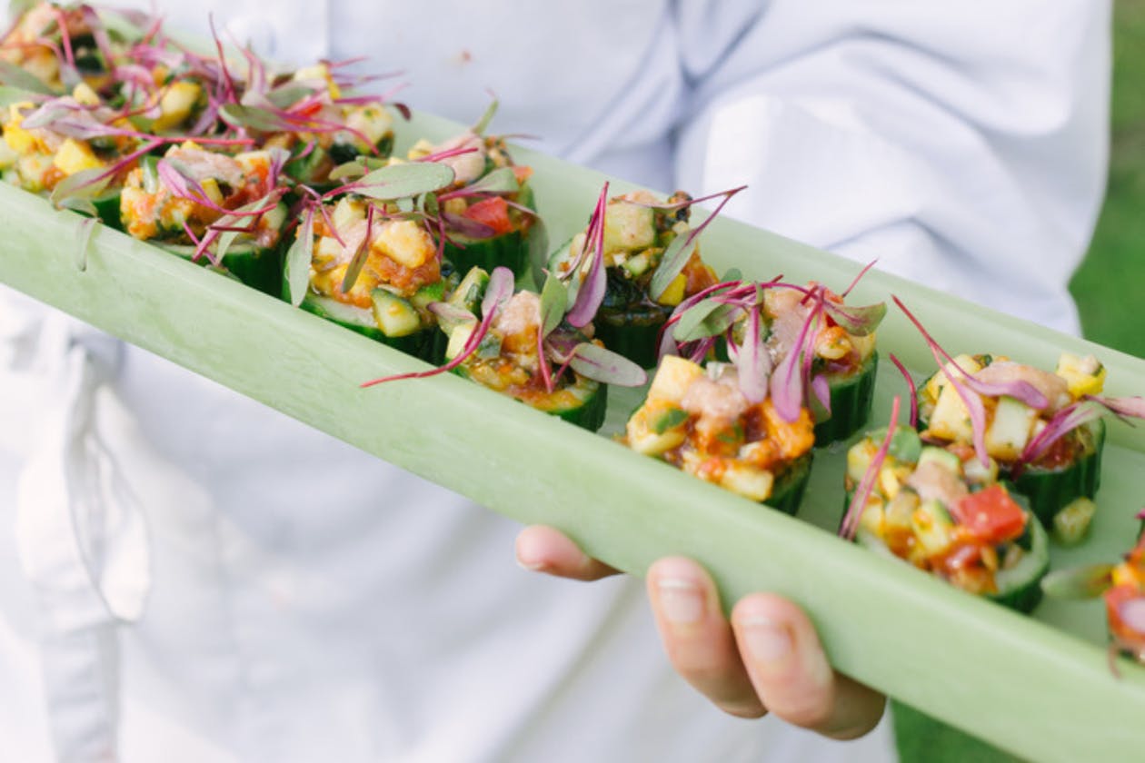 server holding small appetizers on a green tray | PartySlate