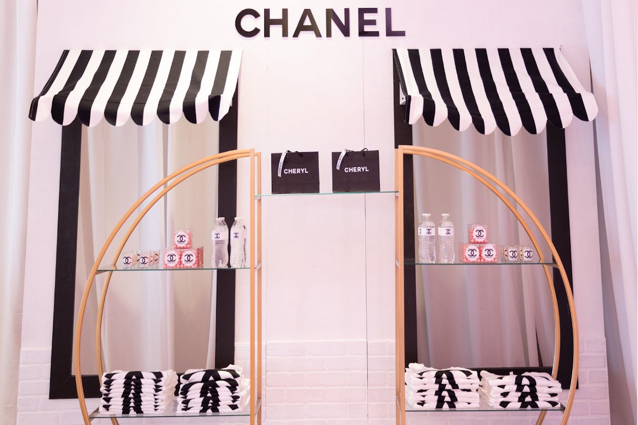 party favors sitting on shelves at pink Chanel themed 60th birthday party | PartySlate
