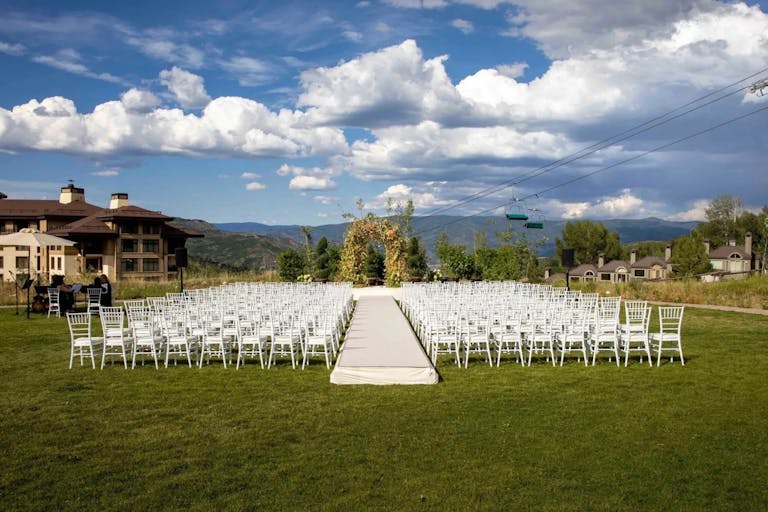 Viceroy Snowmass wedding ceremony outside on main lawn with mountains in the background | PartySlate