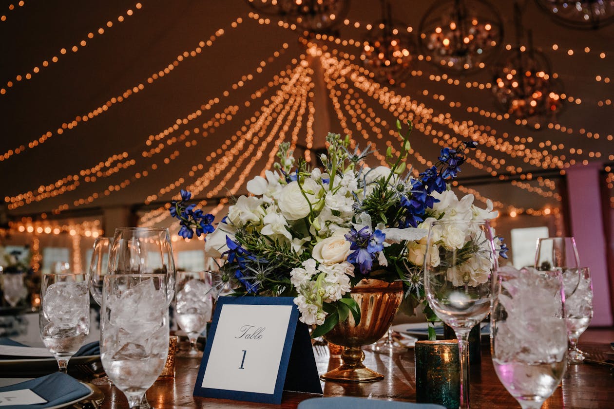 Tented wedding with string lights and blue floral centerpieces | PartySlate